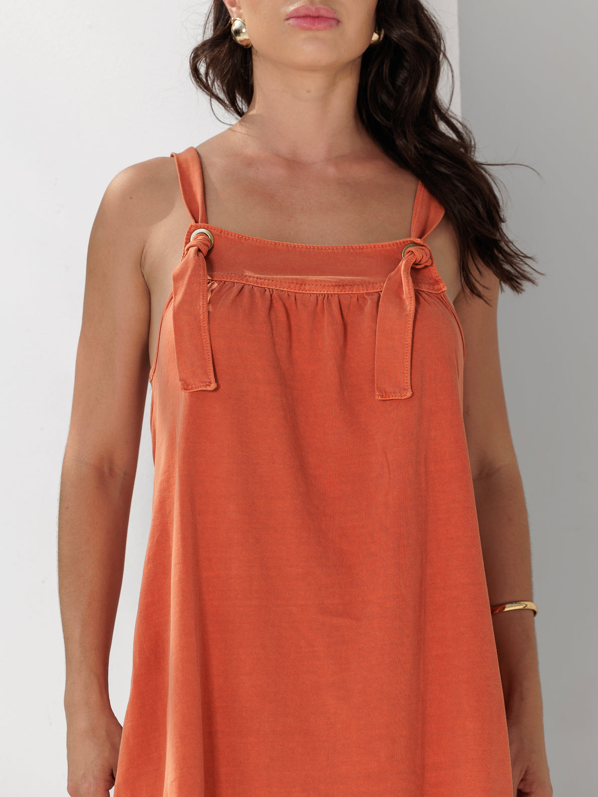 Modelo veste Vestido Sarah Coral em 100% algodão, com alças ajustáveis em ilhós e caimento fluido